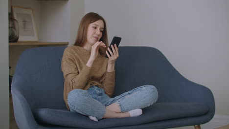 Happy-young-lady-student-is-talking-on-mobile-phone-holding-smartphone-in-apartment.-Modern-communication-cheerful-millennials-and-leisure-time-concept.